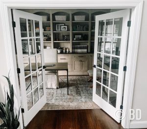 french doors open looking into office with cabinetry