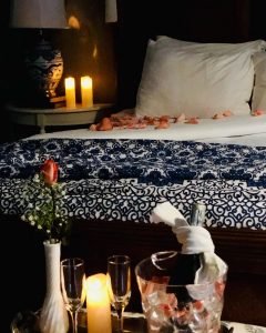 Large bed with candles, flowers, and champagne